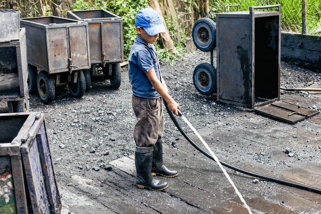 Photo A young boy hoses down spoil outside the entrance of the Coscuez mine. 